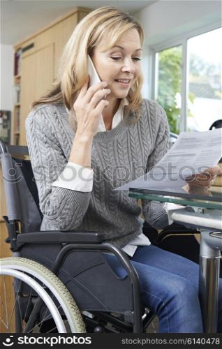 Woman In Wheelchair Making Phone Call Whilst Reading Letter