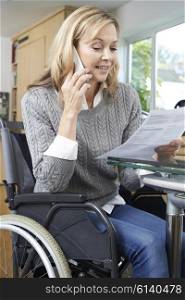 Woman In Wheelchair Making Phone Call Whilst Reading Letter
