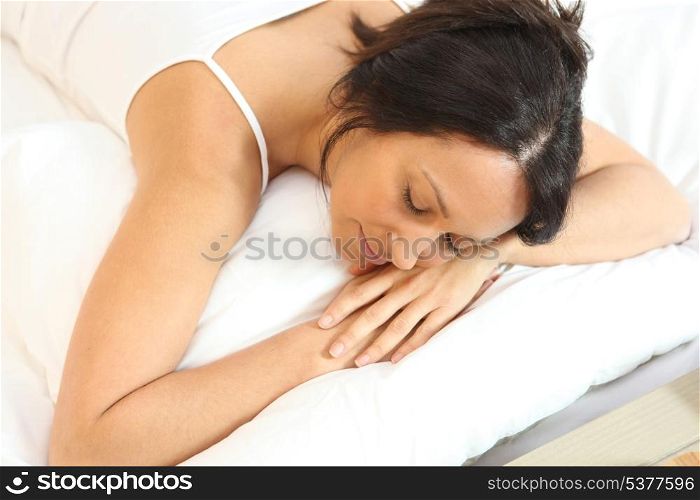 Woman in white asleep on a white bed