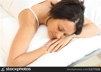 Woman in white asleep on a white bed