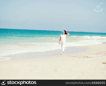 Woman in white clothes on the beach on sunny day. Beautiful day on the beach