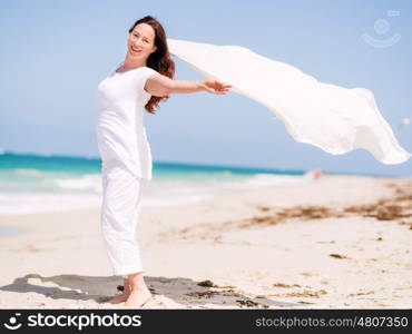 Woman in white clothes on the beach on sunny day. Beautiful day on the beach