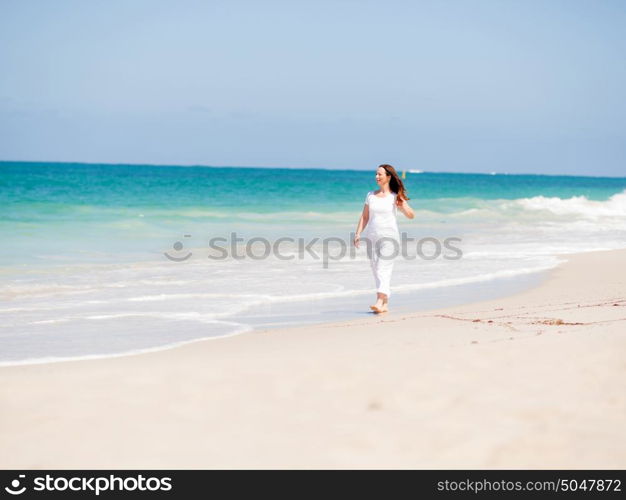 Woman in white clothes on the beach on sunny day. Beautiful day on the beach