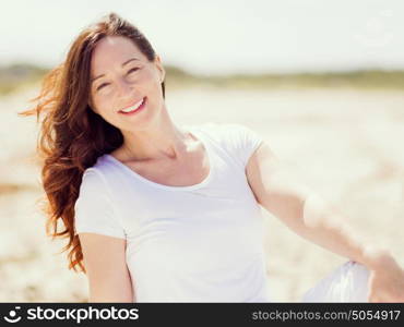 Woman in white clothes on the beach on sunny day. Beautiful day on the beach