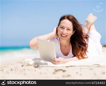 Woman in white clothes on the beach with tablet. Always connected
