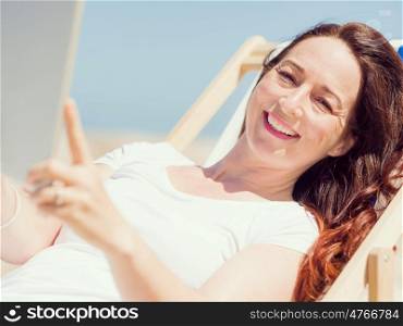 Woman in white clothes on the beach with tablet. Always connected