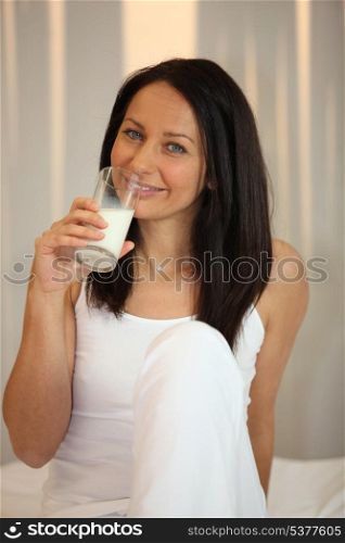 Woman in white drinking a glass of milk