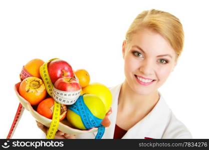 Woman in white lab coat holding fruits and colorful measure tapes isolated. Doctor dietitian recommending healthy food. Diet.