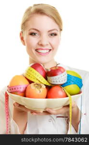 Woman in white lab coat holding fruits and colorful measure tapes isolated. Doctor dietitian recommending healthy food. Diet.