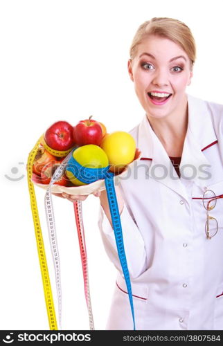 Woman in white lab coat recommending healthy food. Doctor dietitian holding bowl of fruits and colorful measture tapes isolated. Diet.