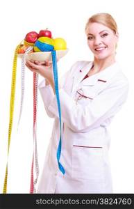Woman in white lab coat recommending healthy food. Doctor dietitian holding bowl of fruits and colorful measture tapes isolated. Diet.