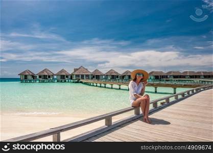 Woman in white on a tropical beach jetty at Maldives