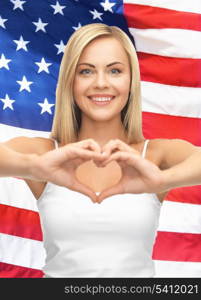 woman in white tank showing heart shape with hands over american flag