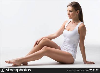 Woman in white underwear sitting on floor on white background. Woman in underwear sitting