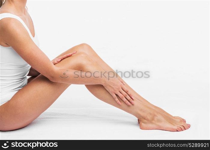 Woman in white underwear. Young beautiful woman in white cotton underwear sitting and touching legs