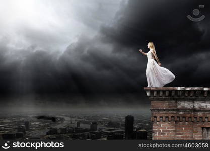 Woman in white. Young woman in white long dress on top of building