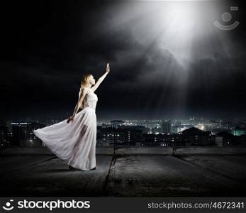 Woman in white. Young woman in white long dress on top of building