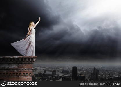 Woman in white. Young woman in white long dress on top of building