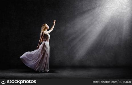 Woman in white. Young woman in white long dress reaching to light