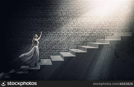 Woman in white. Young woman in white long dress walking up the staircase