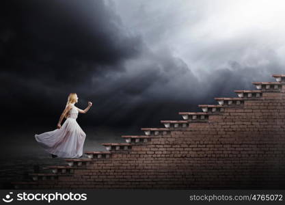 Woman in white. Young woman in white long dress walking up the staircase