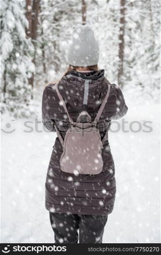 Woman in winter jacket walking in snowy winter forest, snowy winter day. Woman walking in snowy winter forest