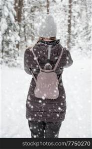 Woman in winter jacket walking in snowy winter forest, snowy winter day. Woman walking in snowy winter forest