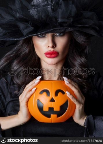 Woman in witch costume hold Halloween pumpkin bucket for candies close up beauty portrait. Witch with Halloween pumpkin