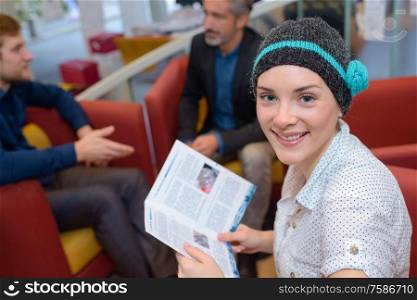 Woman in woolly hat reading brochure