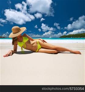 Woman in yellow bikini lying on tropical beach at Seychelles