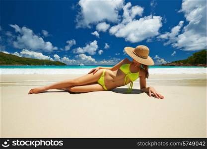 Woman in yellow bikini lying on tropical beach at Seychelles