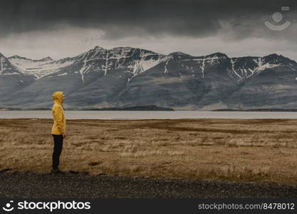 Woman in yellow contemplating the landscape; Iceland