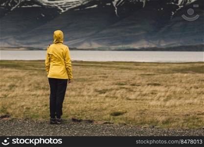 Woman in yellow contemplating the landscape  Iceland