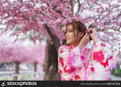 woman in yukata  kimono dress  looking sakura flower or cherry blossom blooming in the garden