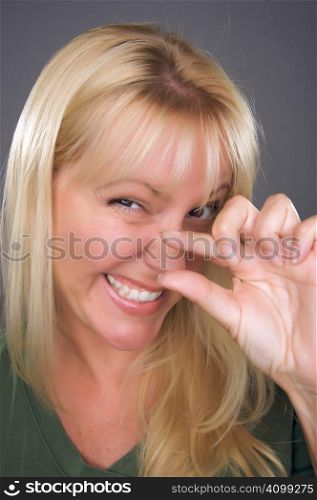 Woman Indicating A Little Bit with Her Hand Against a Grey Background.