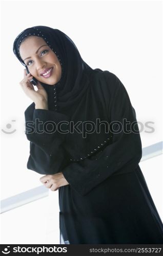 Woman indoors using cellular phone and smiling (high key/selective focus)
