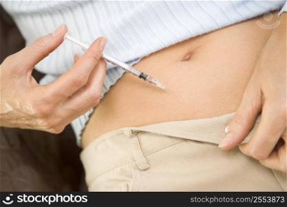 Woman injecting drugs to prepare for IVF treatment (selective focus)