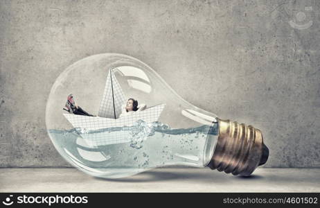 Woman inside light bulb. Young businesswoman floating on paper boat inside of light bulb