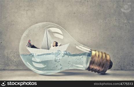 Woman inside light bulb. Young businesswoman floating on paper boat inside of light bulb