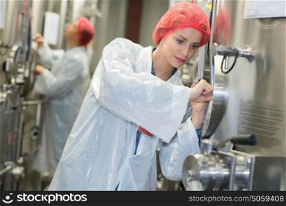woman inspecting wine vats inside winery