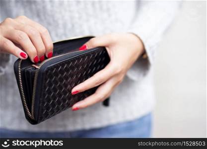 Woman is carrying wallet,she is paying for the product. at the mall