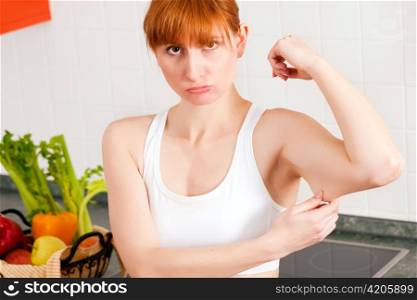 Woman is checking her triceps and seems to be unpleased