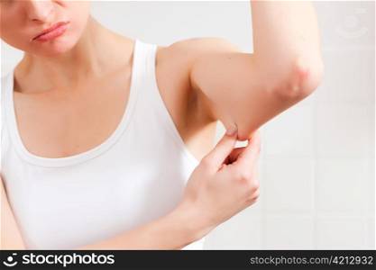 Woman is checking her triceps and seems to be unpleased
