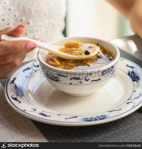 Woman is eating chinese vegetable soup at the restaurant