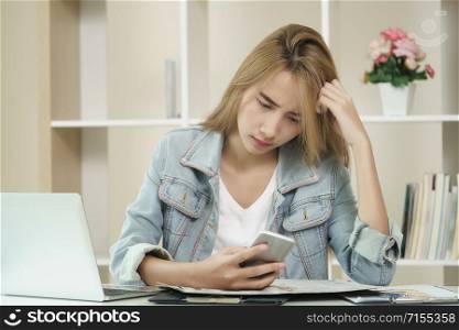 Woman is feeling unhappy and nervous while looking at the smartphone screen in an office.