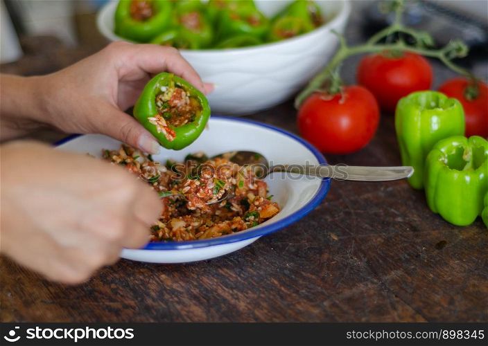 Woman is filling with rice and meat the green pepper. Turkish cuisine food the stuffed pepper.