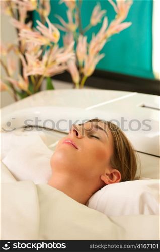 Woman is getting a soft pack in a Spa - she is doing wellness and seems to be very relaxed