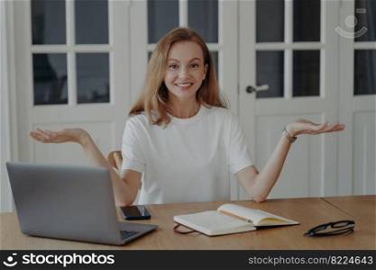 Woman is happy and puzzled. Successful mid adult businesswoman is working from home. Lovely european lady in white t-shirt is freelancer having remote work in her apartment. Concept of work easiness.. Woman is happy and puzzled, concept of work easiness. Successful mid adult businesswoman at home.