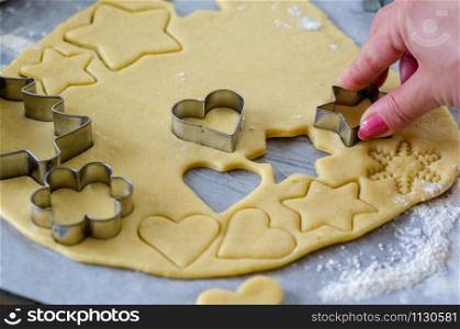 Woman is making Christmas gingerbread cookies in the kitchen.