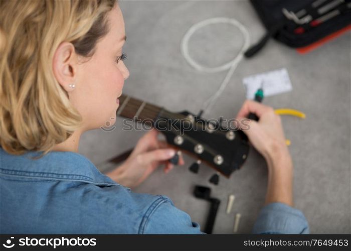 woman is repairing a guitar